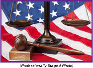 Staged photo with a gavel and scales of justice in front of an American flag.